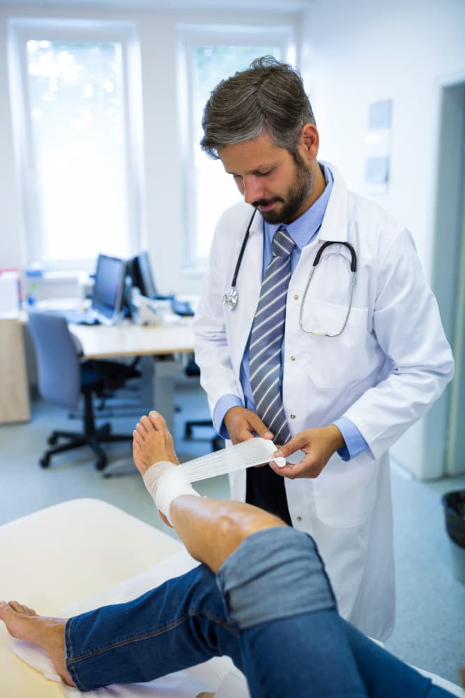 Doctor applying a bandage on the leg of a patient in the Orthopedics and Traumatology Department of Prakash Hospital.